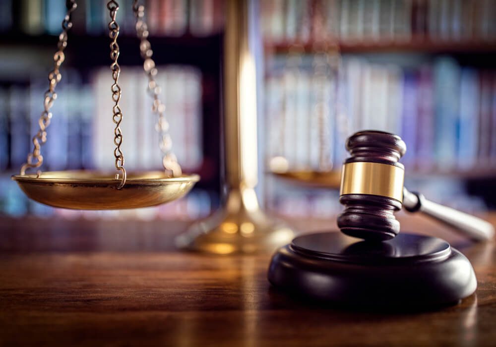 a wooden judge's scale with a bookcase in the background.