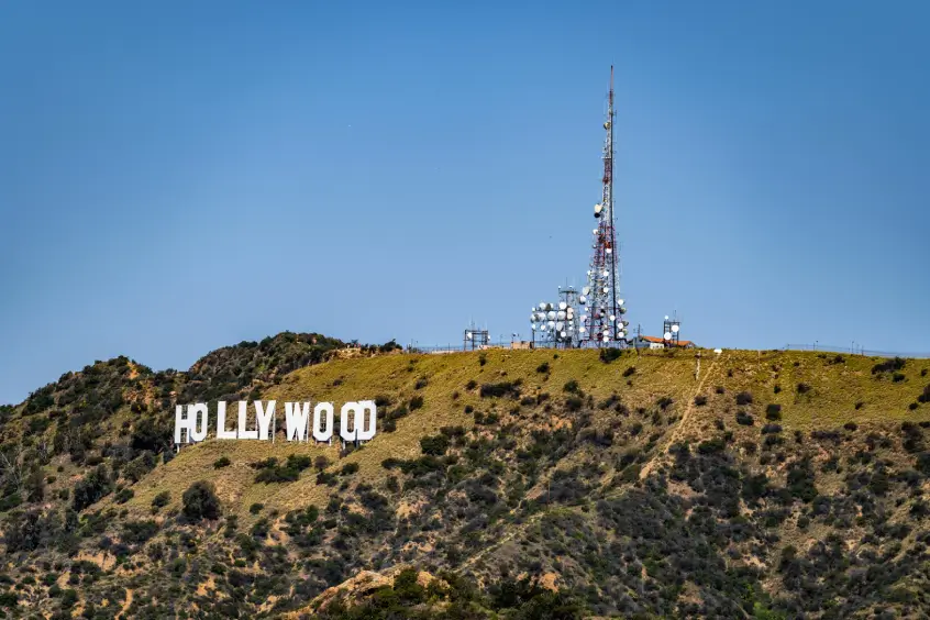 The iconic Hollywood sign, a symbol of reputation management for celebrities, on a hillside with a communication tower in the background, under a clear blue sky.