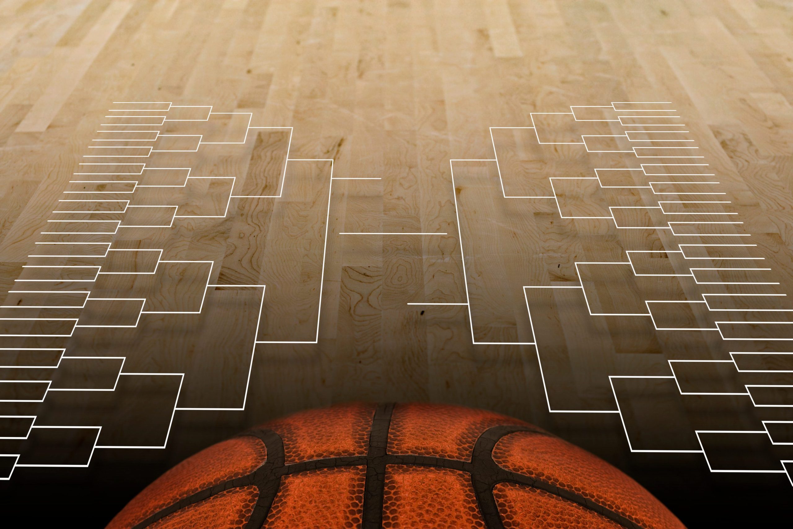 A basketball sits at the foreground on a wooden court with an empty March Madness bracket projection above it, suggesting the anticipation of exciting matchups and fierce competition.