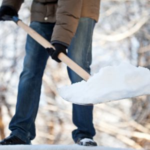 A person shoveling snow on a cold day, demonstrating winter chores and the importance of warm clothing.