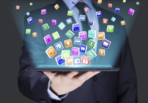 A person holding a laptop with social media icons coming out of it.