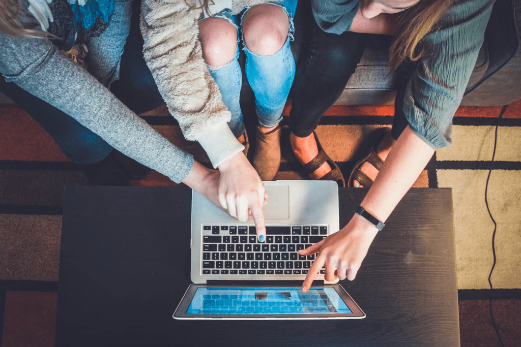 a group of people sitting around a laptop computer.