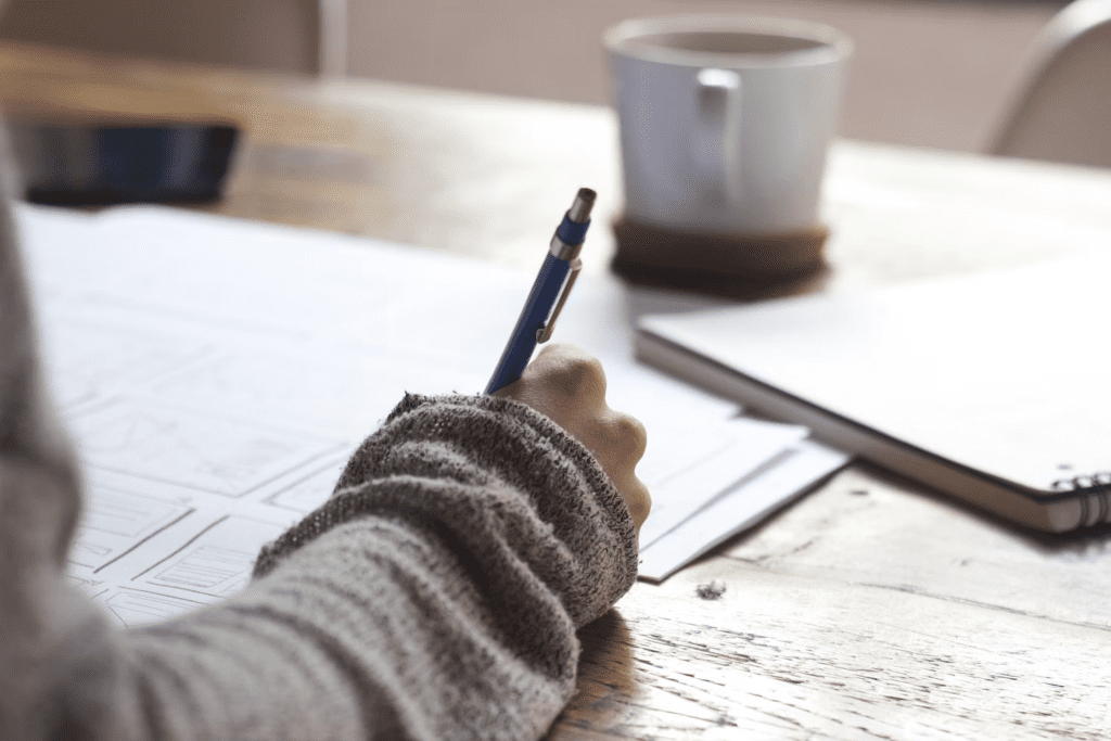 a person writing on a piece of paper with a pen.