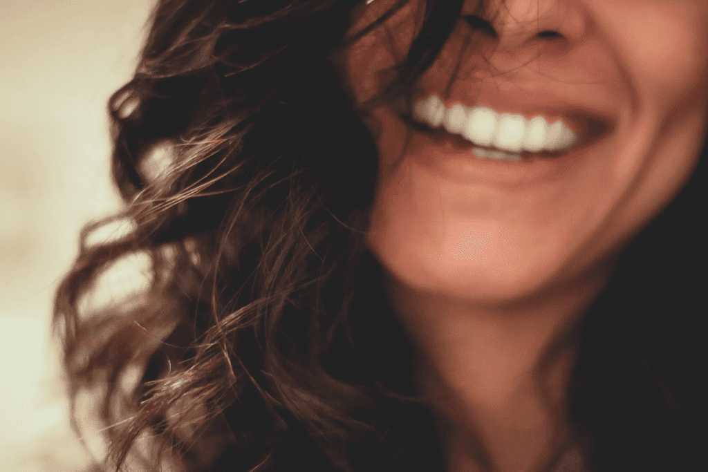 a close up of a woman smiling and holding a cell phone.