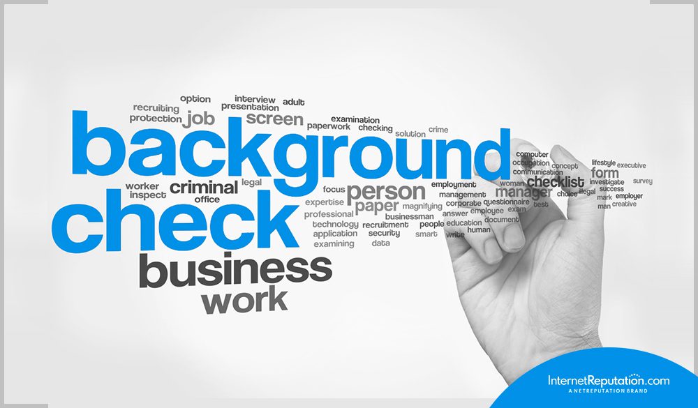 A hand writing the word background check on a white background.