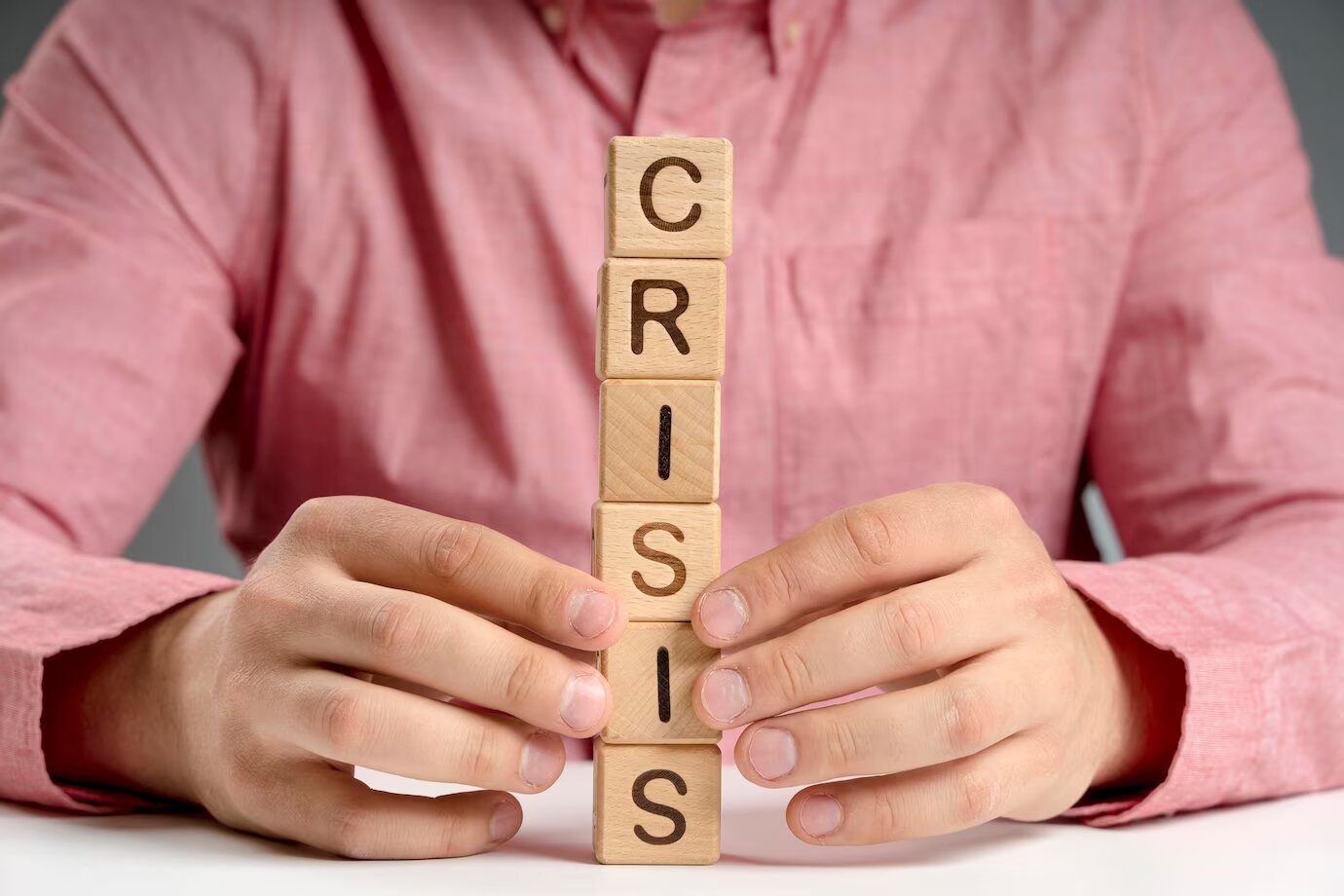 a man holding wooden blocks with the word crisis written on them.
