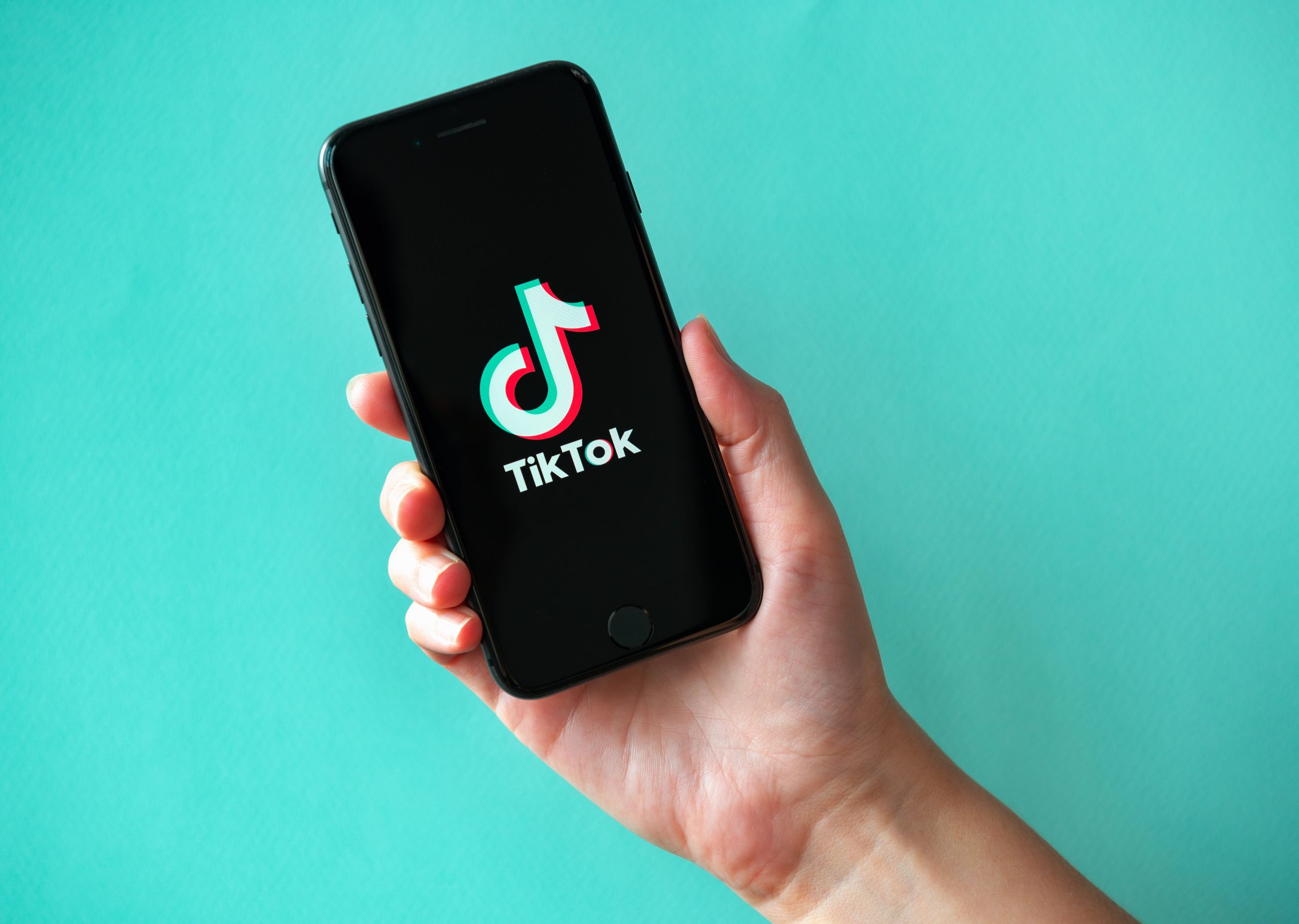 A person holding a phone with the tiktok logo on it.