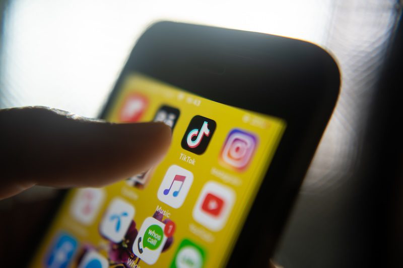 A close-up of a person’s finger about to tap the TikTok app icon on a smartphone screen, with other social media app icons like Instagram and WhatsApp visible, highlighting TikTok’s reputation among popular platforms.