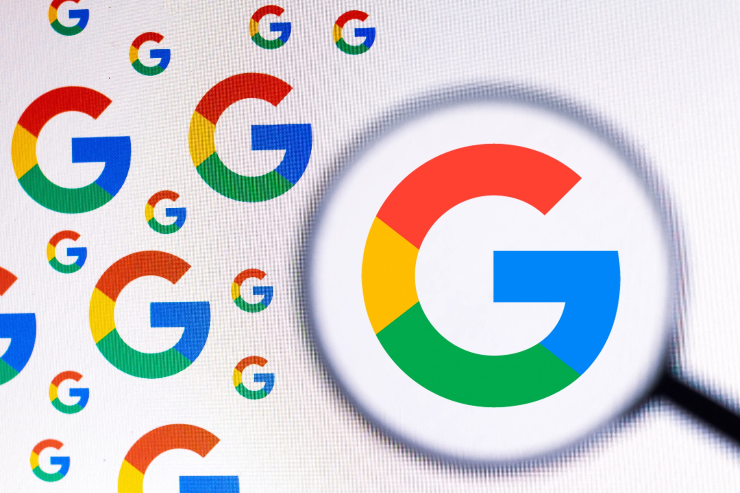 Google logos under a magnifying glass.