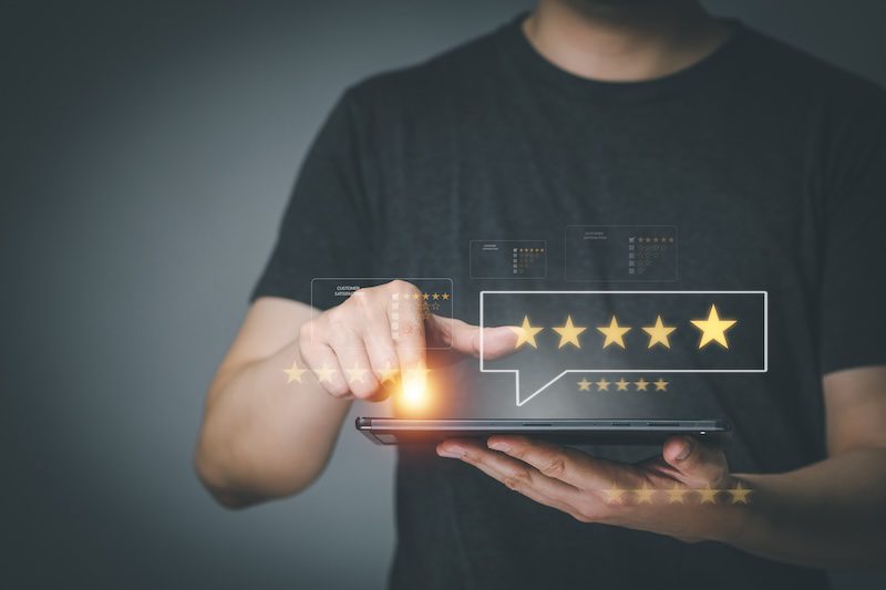 A person using a tablet, touching a screen with a glowing five-star rating graphic, symbolizing giving positive feedback or a high review—an ideal scenario for showcasing the results delivered by the best reputation management services.