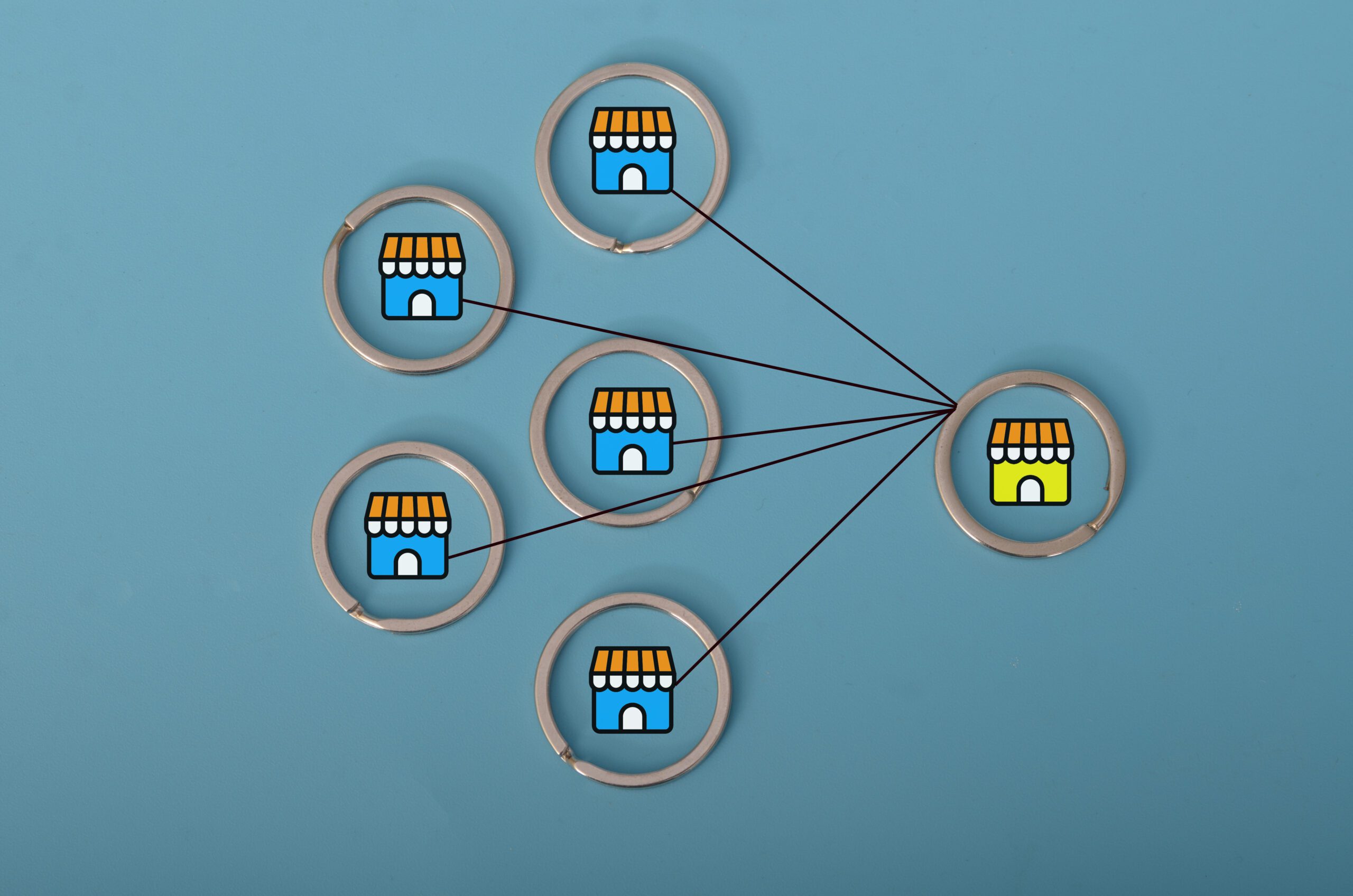 A diagram on a blue background shows five blue storefront icons connected by lines to one green storefront icon, illustrating a network or franchise model.