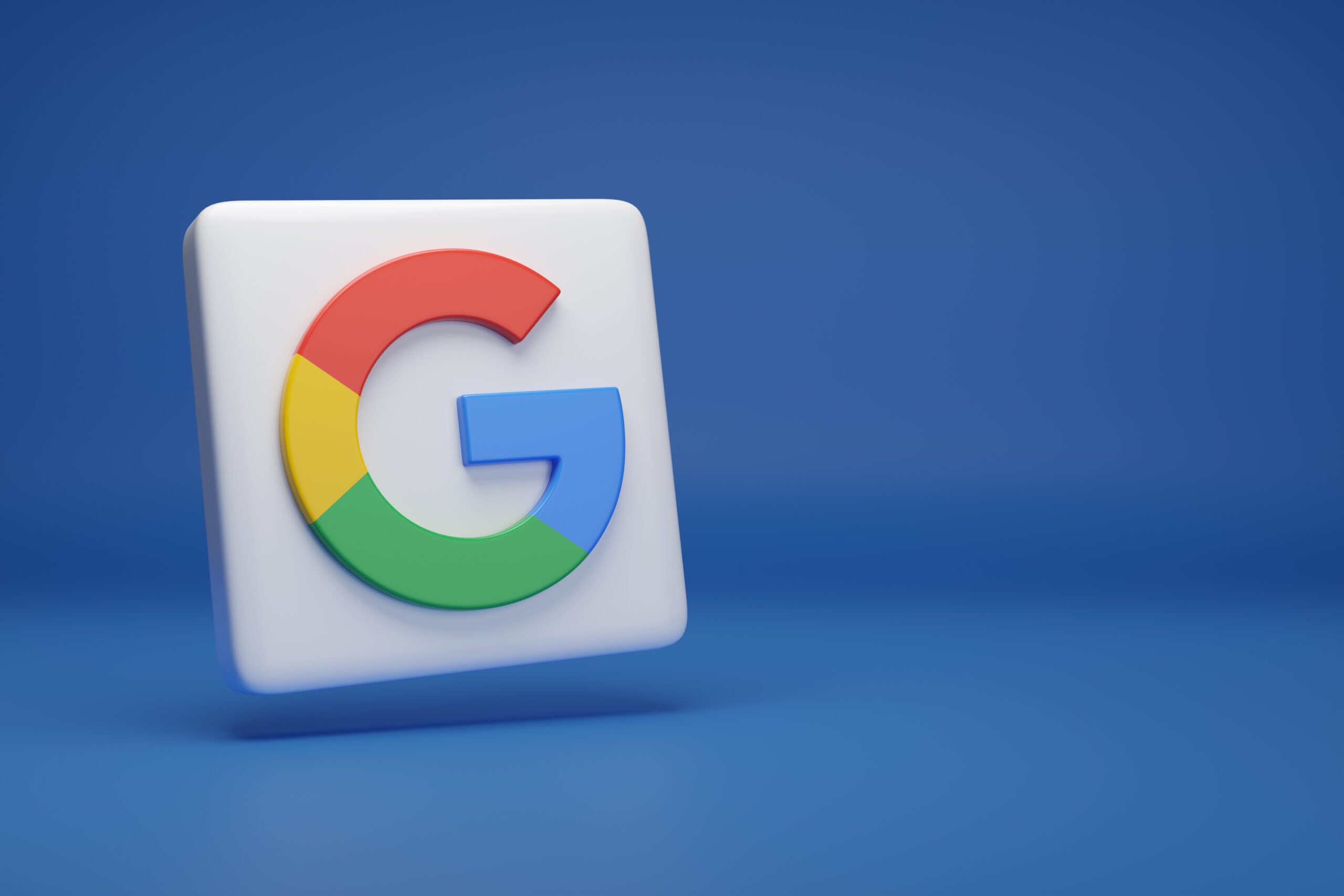 A 3D white square button with the colorful Google "G" logo, featuring blue, red, yellow, and green segments, is set against a plain blue background.