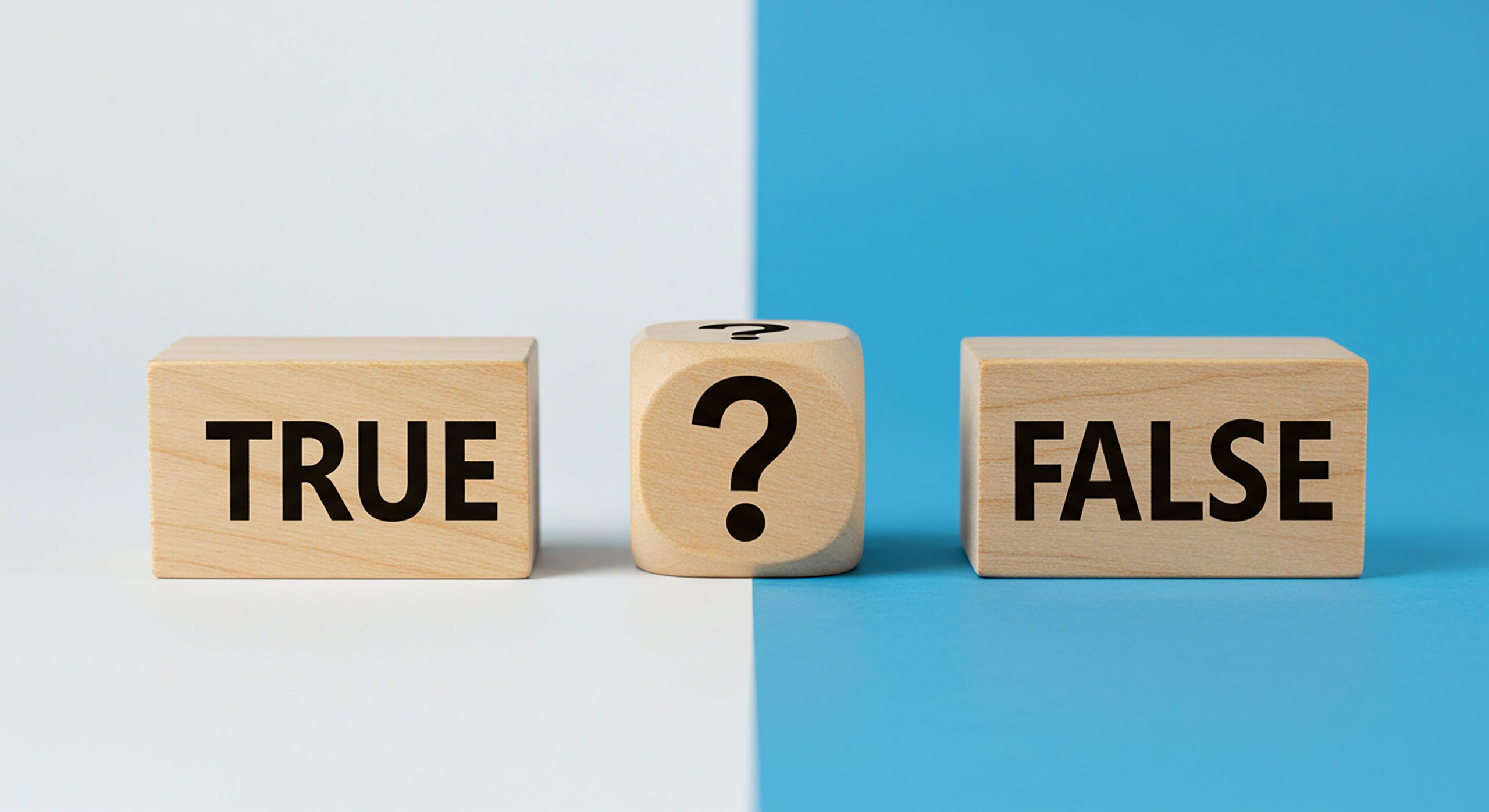 Three wooden blocks on a split white and blue background; the left block reads "TRUE," the right block reads "FALSE," and the center block shows a large question mark.