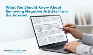 A person holds a pen and points at a laptop screen displaying an article with a pop-up about removing negative articles from the internet. Text on the image reads, "What You Should Know About Removing Negative Articles From the Internet.